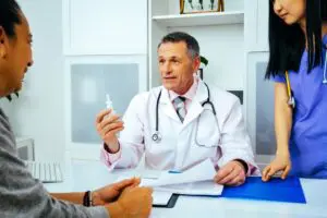 A doctor holding something while sitting in front of two other doctors.