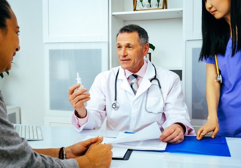 Picture6 A doctor holding something while sitting in front of two other doctors.